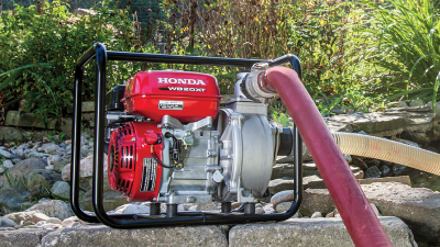 Wide view of transfer pump sitting on stones with hose plugged in. 