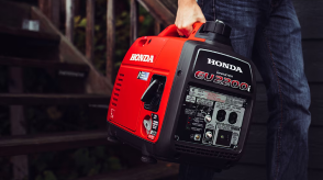 Gros plan d’une personne transportant une génératrice Honda portable.  