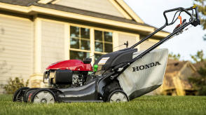 A Honda lawn mower sits outside a home.  