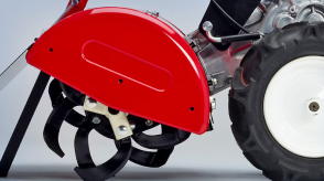 Closeup side view of tiller on white space, showcasing the rotor shaft and tines. 